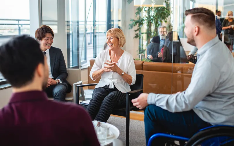 A diverse group of people in a bright office setting, engaged in a lively discussion. 
