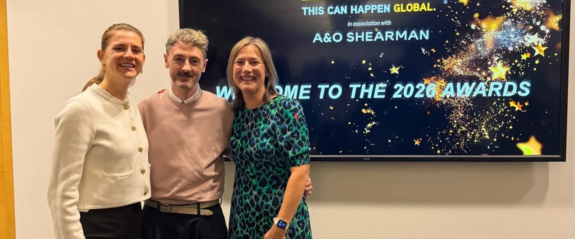 CiC Wellbeing team members at This Can Happen Awards event stood in front of the awards screen