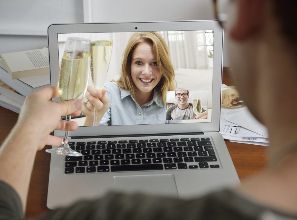 Two people raise a glass of champagne over a video call