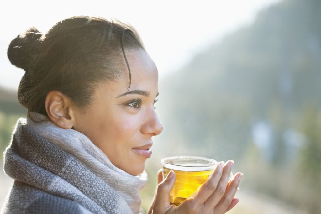 Woman in scarf drinking tea outside