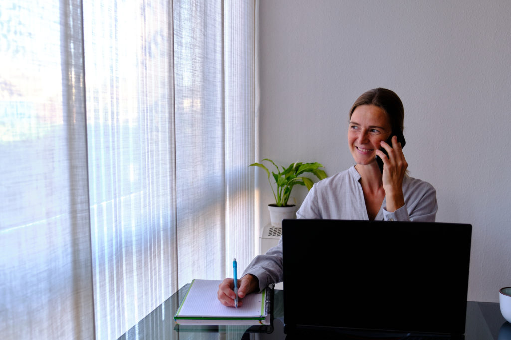 woman smiling on the phone with a laptop