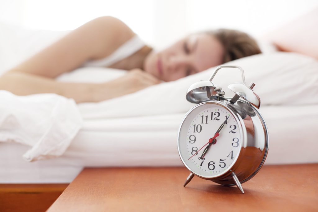 Woman sleeping behind alarm clock