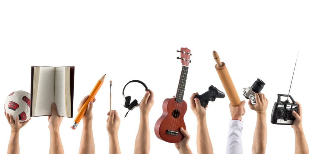 Hands holding up balls, books and instruments to show new hobbies