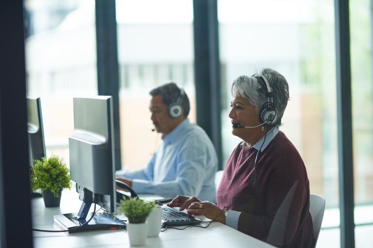 Photo of woman and man with telephone headsets talking to a caller