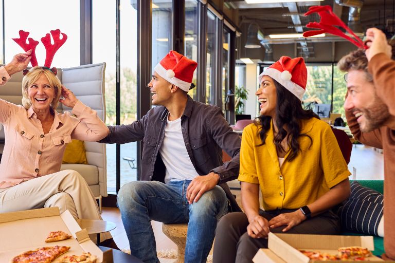 Photo of 2 women and 2 men at work wearing santa hats